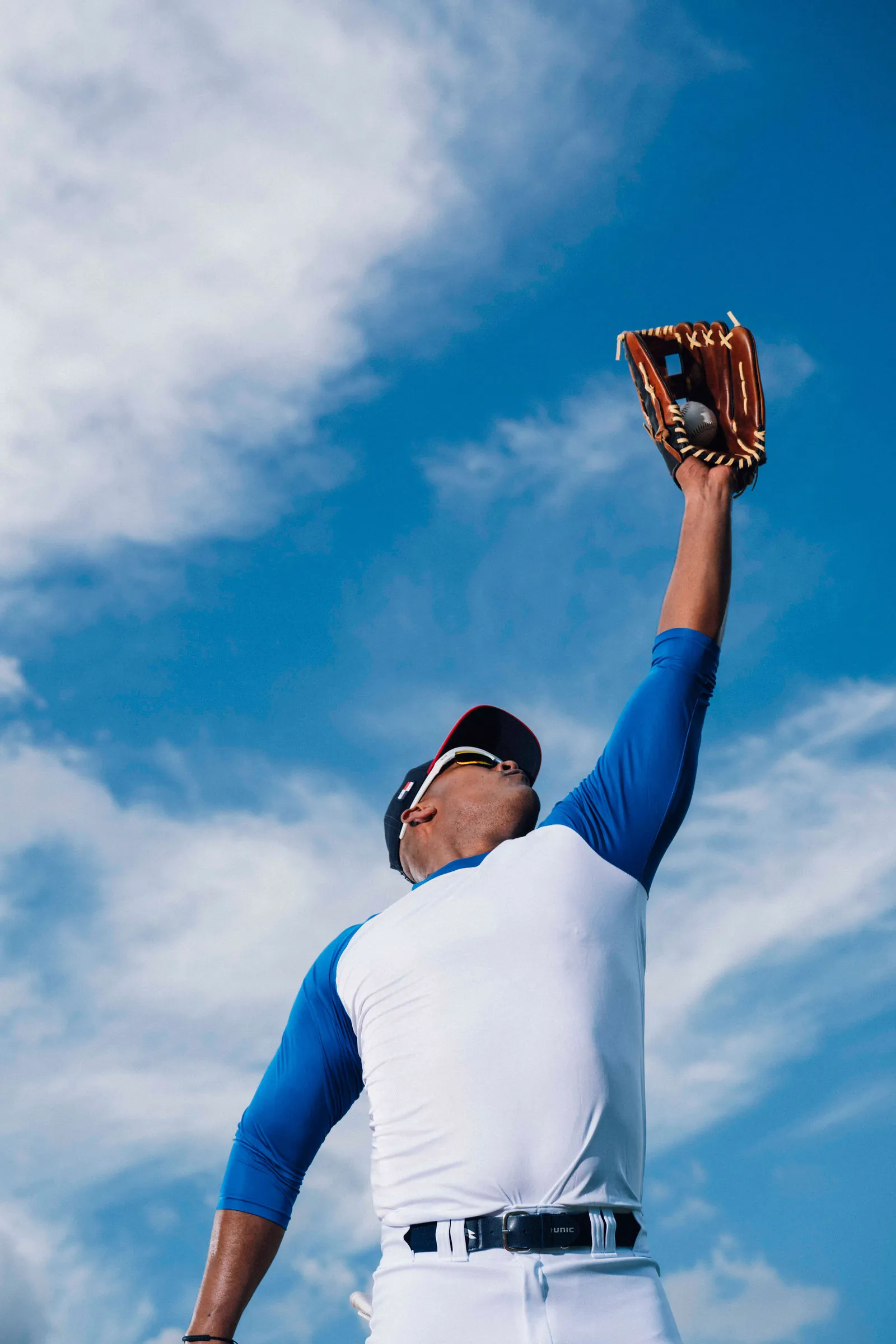 Jugador de béisbol estira el guante hacia el cielo para atrapar la pelota